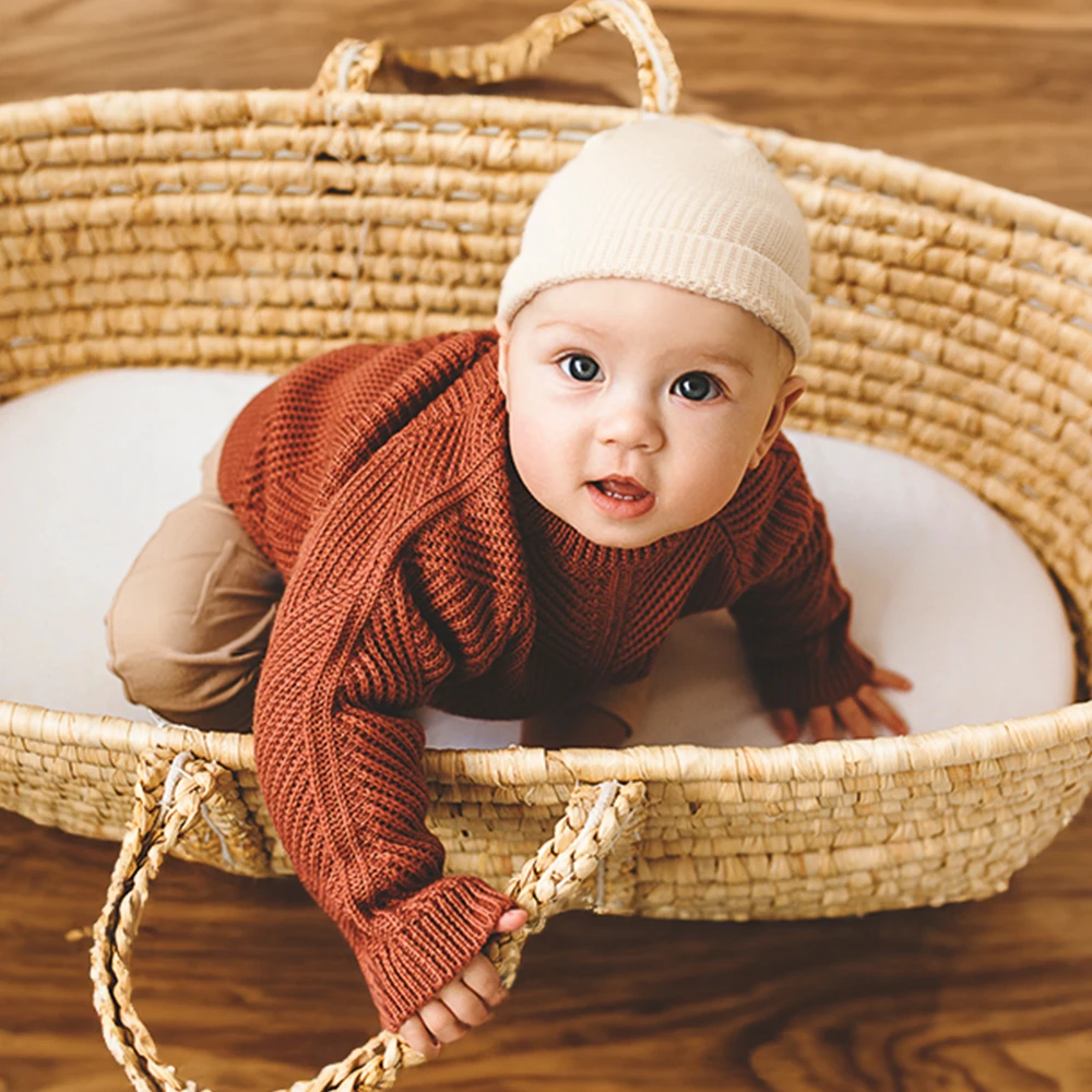 Baby mit babykleidung im Korb