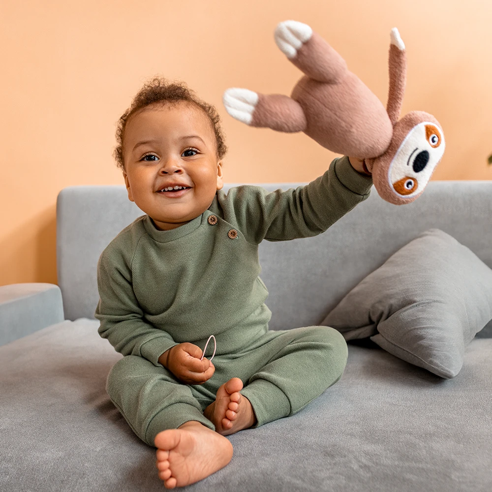 Baby mit huebscher babykleidung und stofftier