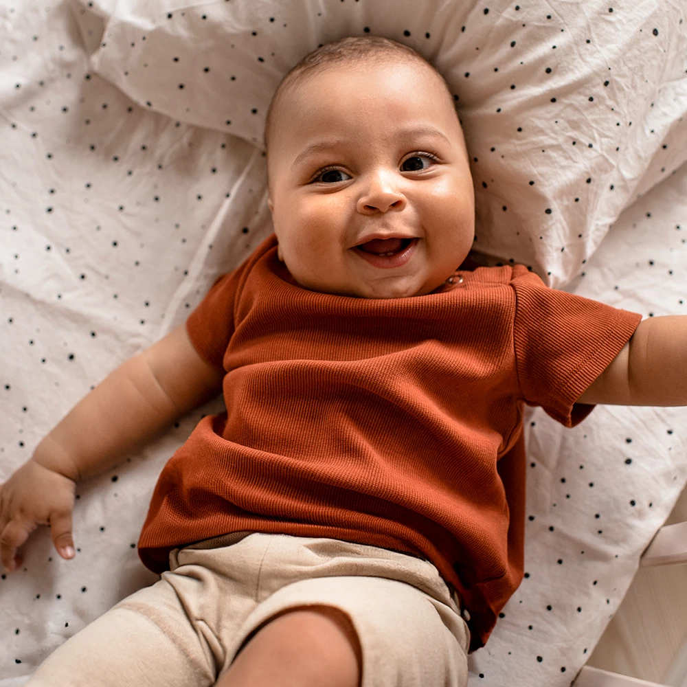 Glückliches Baby lachend im Bett