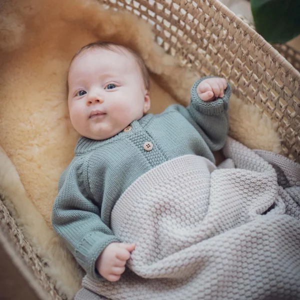 Baby liegt in der Wiege mit Jacke León Sage